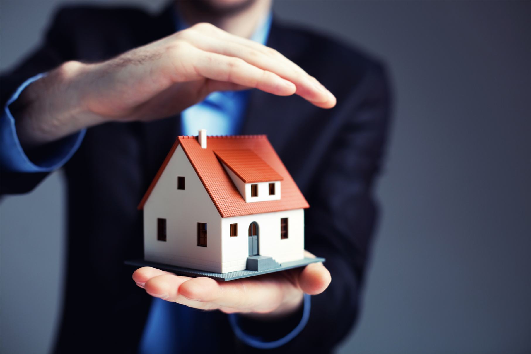 Hand holding a small house, representing home insurance protection